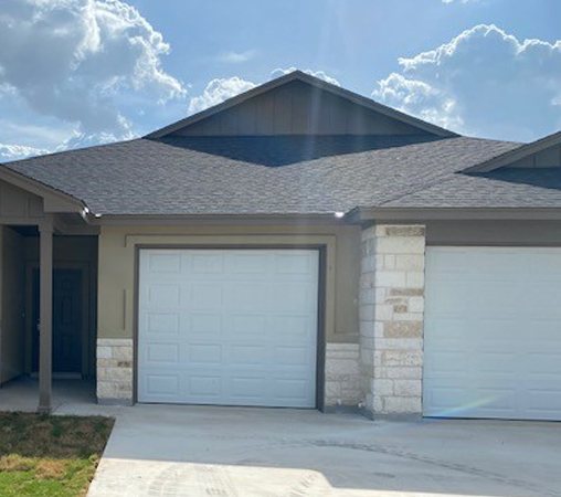 Single-story duplex with board-and-batten gable, stone columns and white garage doors