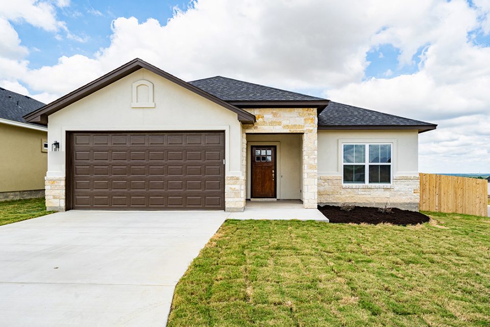 Single-story home with stone and stucco front, dark brown garage door and new sod lawn