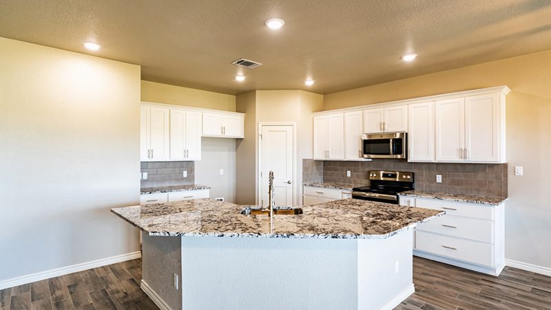 Kitchen with white shaker cabinets, granite island and wood-look tile floor