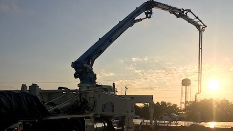 Concrete pump truck boom extended against a sunrise sky